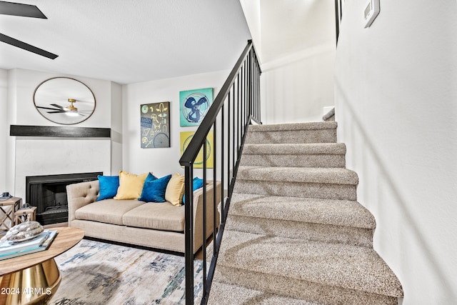 stairs with ceiling fan and a textured ceiling