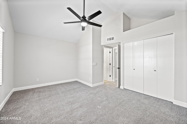 unfurnished bedroom with high vaulted ceiling, a closet, ceiling fan, and carpet flooring