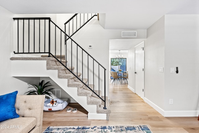 stairway featuring hardwood / wood-style flooring and a notable chandelier