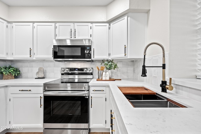 kitchen featuring decorative backsplash, white cabinetry, sink, and stainless steel appliances