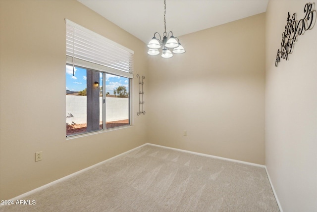 carpeted spare room featuring a chandelier