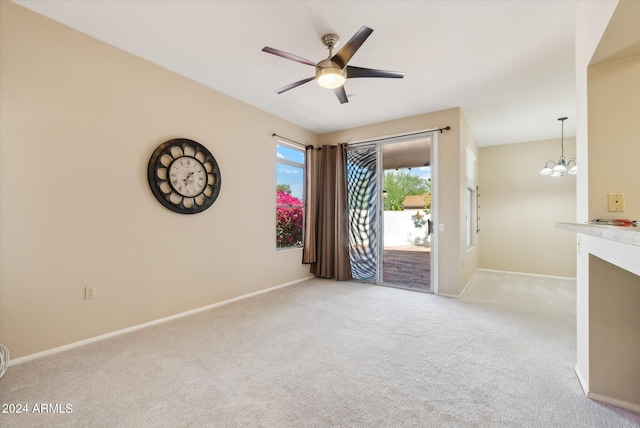 unfurnished room featuring ceiling fan with notable chandelier and light colored carpet