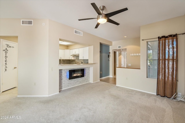 unfurnished living room featuring ceiling fan and light colored carpet