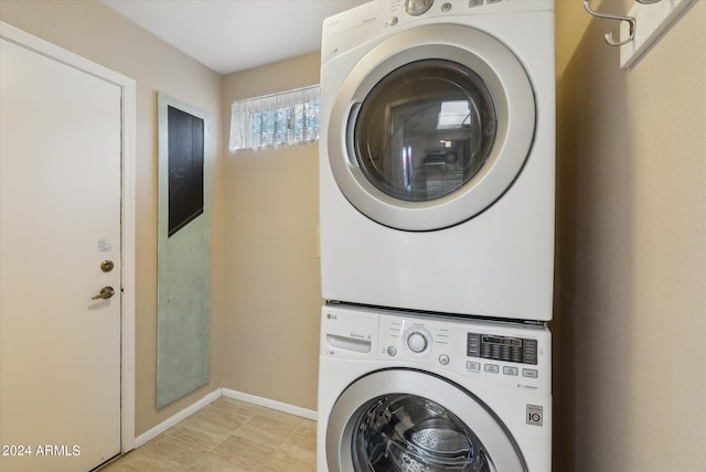 clothes washing area featuring stacked washing maching and dryer and light tile patterned floors