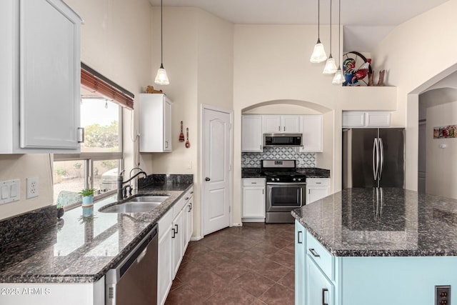kitchen featuring arched walkways, white cabinets, a sink, and stainless steel appliances