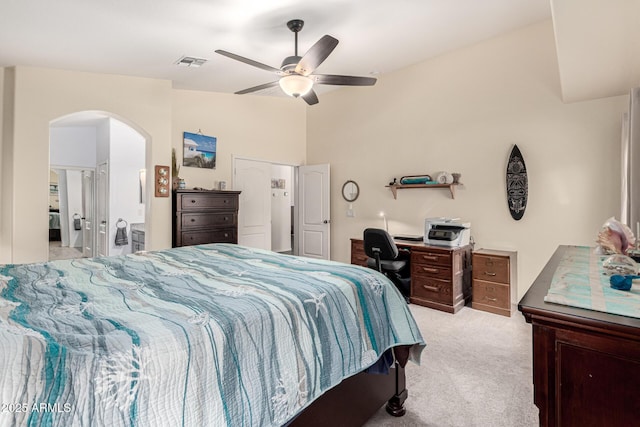 bedroom featuring arched walkways, connected bathroom, ceiling fan, visible vents, and light carpet