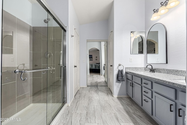 bathroom featuring a shower stall, marble finish floor, a sink, double vanity, and ensuite bathroom