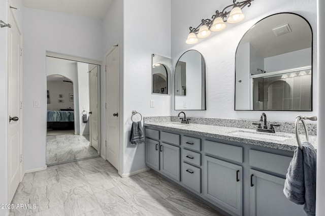 ensuite bathroom with marble finish floor, connected bathroom, a sink, and double vanity