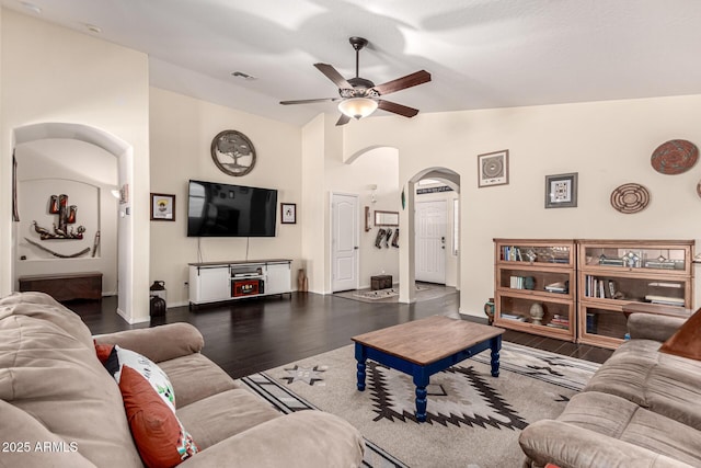 living room with visible vents, wood finished floors, a ceiling fan, arched walkways, and lofted ceiling
