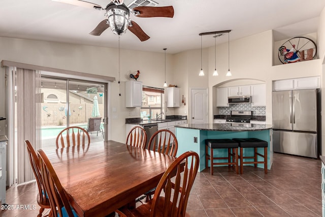 dining area featuring a high ceiling, dark tile patterned flooring, and a ceiling fan
