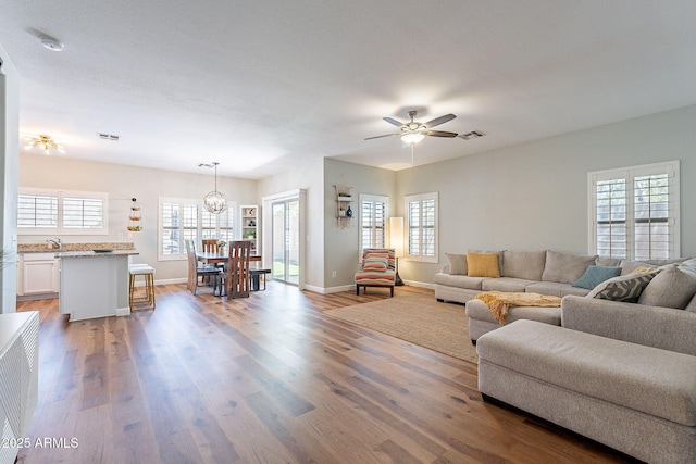 1702 W Wildwood Dr, Phoenix, AZ 85045 - living area featuring wood finished floors, ceiling fan with notable chandelier, baseboards, and visible vents