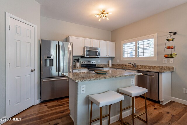1702 W Wildwood Dr, Phoenix, AZ 85045 - kitchen with dark wood-style flooring, a sink, appliances with stainless steel finishes, a kitchen bar, and white cabinetry