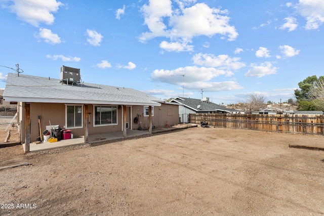 rear view of house featuring a shingled roof, a fenced backyard, a patio, and central AC unit