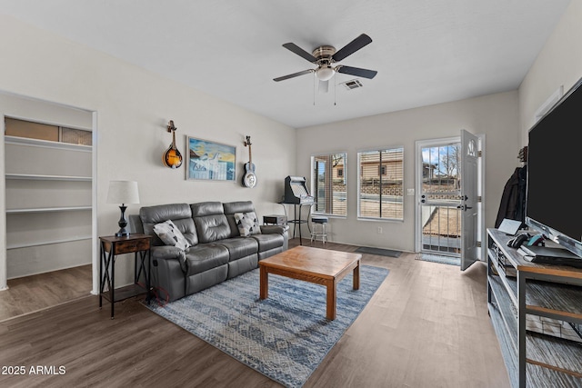 living room featuring visible vents, ceiling fan, and wood finished floors