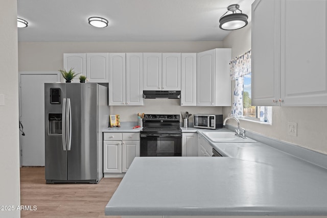 kitchen with under cabinet range hood, appliances with stainless steel finishes, white cabinets, and a sink