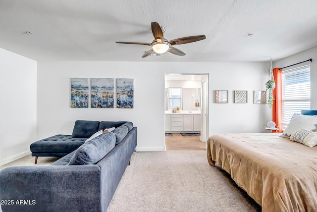 bedroom with light colored carpet, a textured ceiling, ensuite bathroom, and baseboards