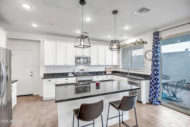 kitchen featuring tasteful backsplash, visible vents, light wood-style flooring, and appliances with stainless steel finishes