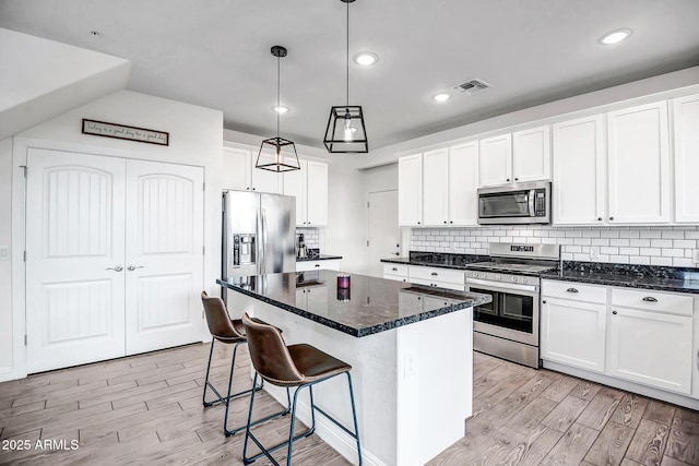 kitchen featuring light wood-style flooring, white cabinets, appliances with stainless steel finishes, and a kitchen island