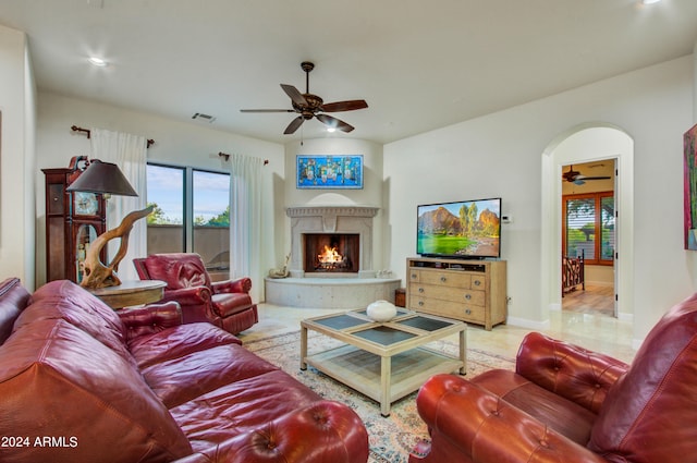 living room featuring a high end fireplace and ceiling fan