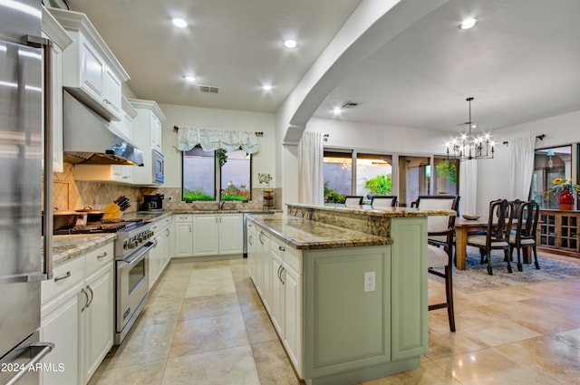 kitchen with hanging light fixtures, a kitchen island, stainless steel appliances, and white cabinetry