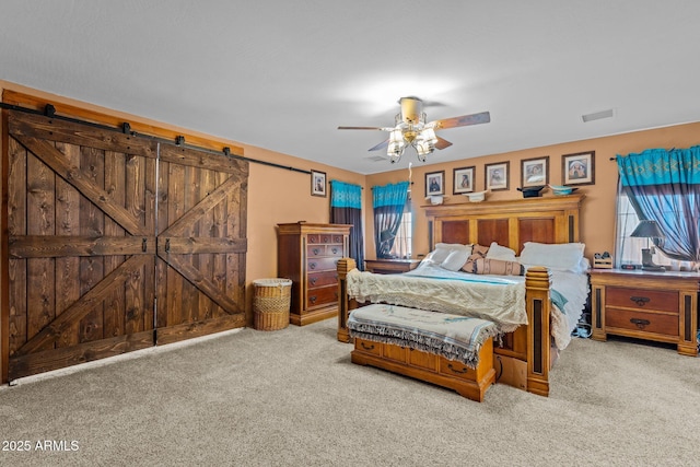 unfurnished bedroom with ceiling fan, carpet, a barn door, and multiple windows