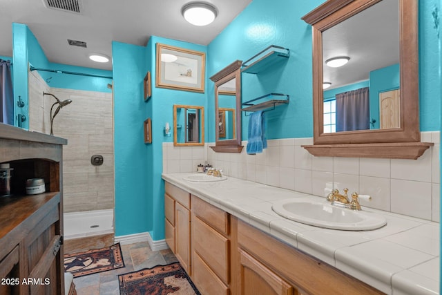 bathroom featuring vanity, decorative backsplash, and tiled shower