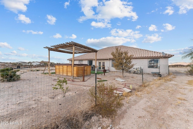 back of property featuring a jacuzzi and a pergola