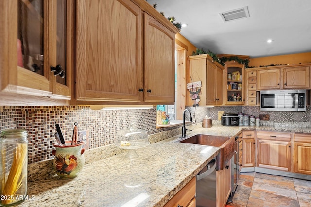 kitchen featuring backsplash, light stone countertops, sink, and stainless steel appliances