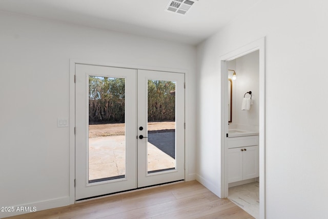 entryway with light wood-type flooring, french doors, visible vents, and baseboards