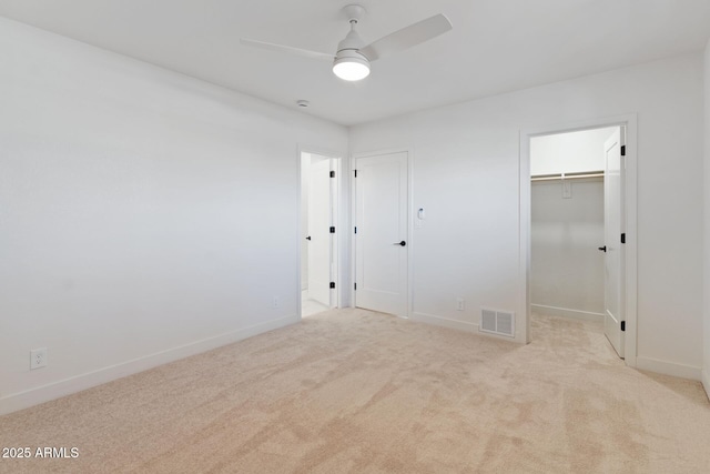 unfurnished bedroom with baseboards, a spacious closet, visible vents, and light colored carpet