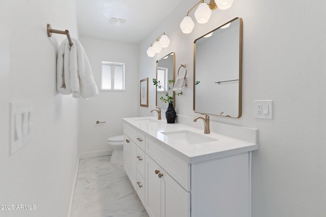 full bathroom with toilet, marble finish floor, double vanity, and a sink