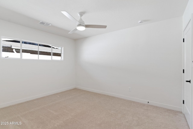 spare room featuring baseboards, ceiling fan, visible vents, and light colored carpet