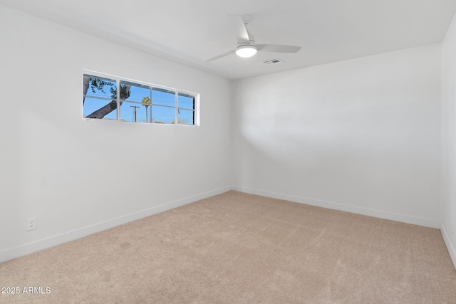 empty room with light carpet, a ceiling fan, visible vents, and baseboards