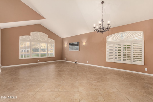 tiled empty room with lofted ceiling and a chandelier