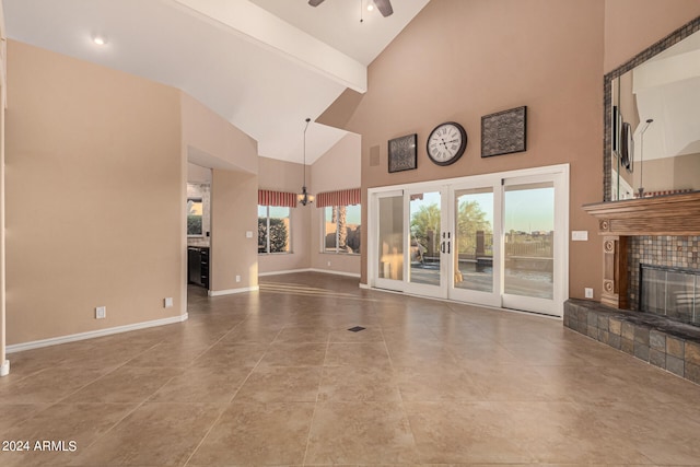 unfurnished living room featuring ceiling fan, beam ceiling, light tile patterned floors, high vaulted ceiling, and a fireplace