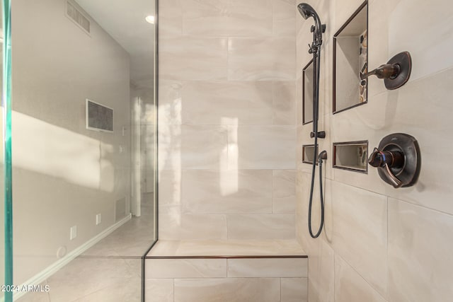 bathroom with tile patterned flooring and a tile shower