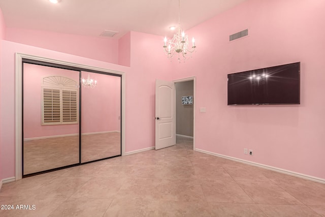 unfurnished bedroom featuring high vaulted ceiling, a closet, and a notable chandelier