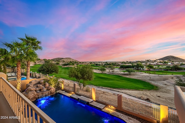 pool at dusk with pool water feature and a mountain view