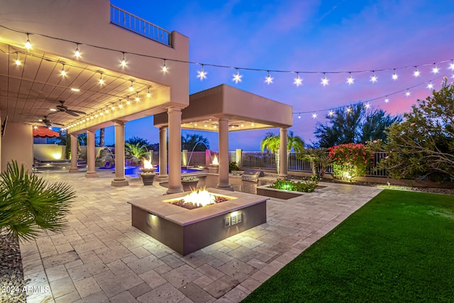 patio terrace at dusk featuring an outdoor fire pit and ceiling fan