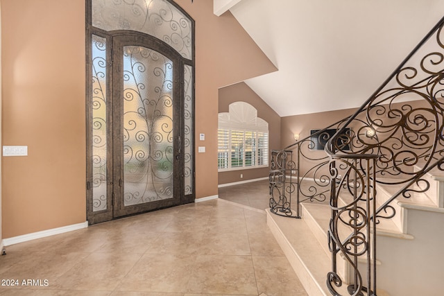 foyer entrance with beam ceiling, light tile patterned floors, and high vaulted ceiling