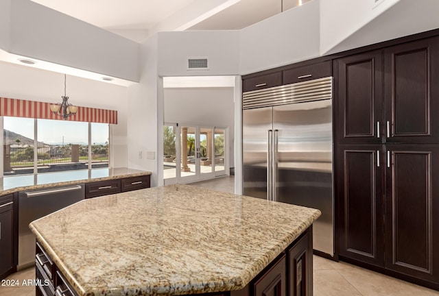 kitchen with a center island, a towering ceiling, stainless steel appliances, and an inviting chandelier