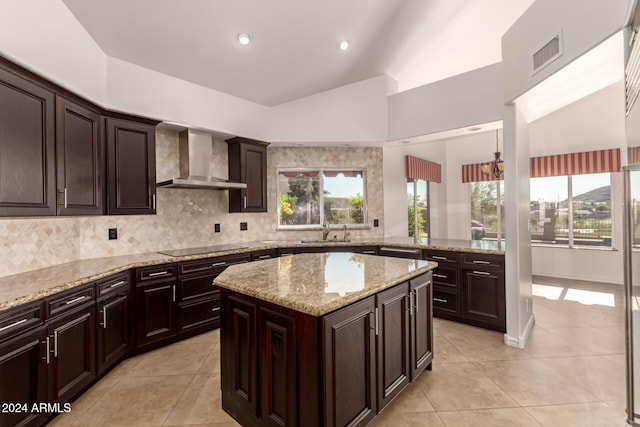 kitchen with decorative backsplash, wall chimney exhaust hood, sink, light tile patterned floors, and a center island