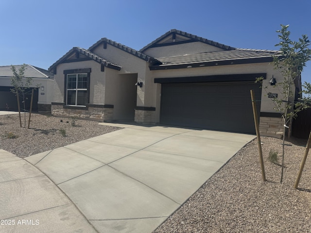 17738 W Onyx Ave, Waddell, AZ 85355 - ranch-style house with concrete driveway, a garage, stone siding, stucco siding, and a tiled roof