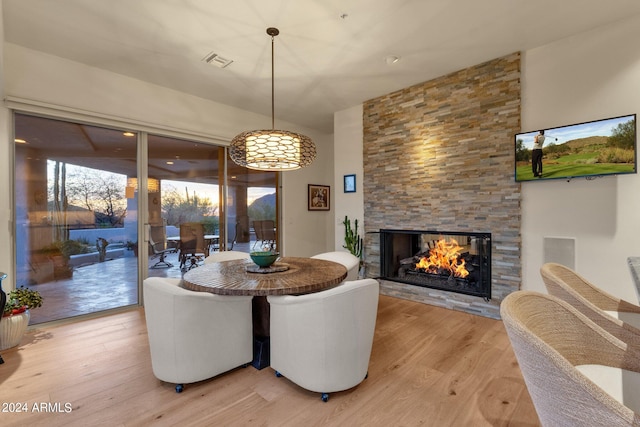 dining room featuring a stone fireplace and wood-type flooring