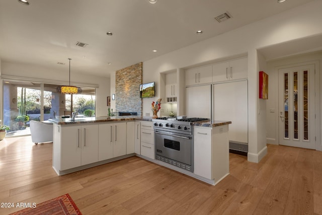 kitchen with white cabinets, decorative light fixtures, kitchen peninsula, and luxury range