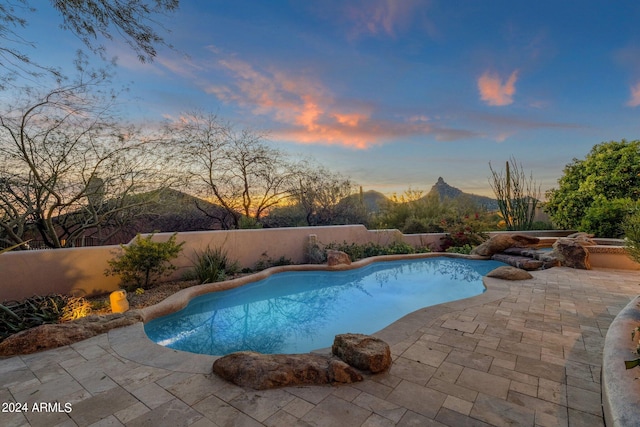 pool at dusk featuring a mountain view and a patio area