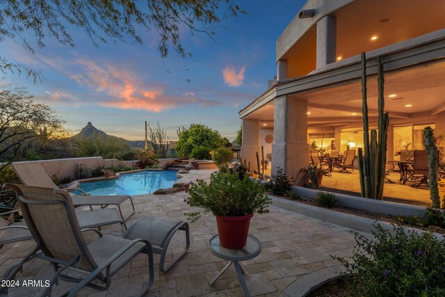 pool at dusk with a mountain view and a patio area