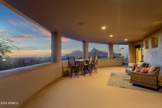 patio terrace at dusk featuring a balcony and a mountain view