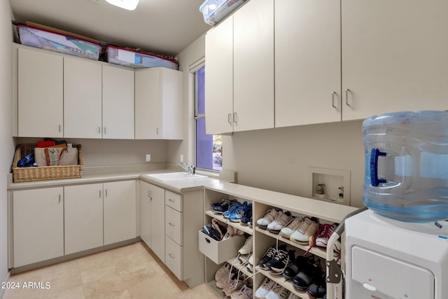 clothes washing area with sink, washer / dryer, and cabinets