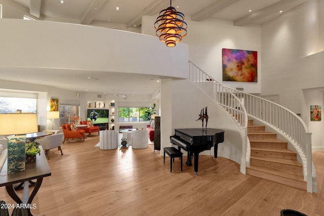 foyer entrance with light hardwood / wood-style floors, a chandelier, beamed ceiling, and a high ceiling